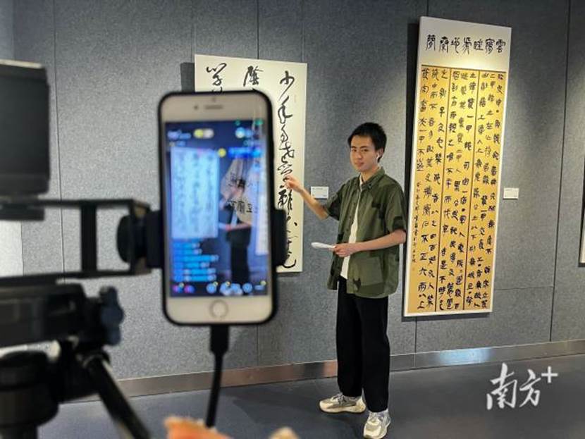 广州新华学院师生艺术作品展在省文化馆展出,网络与新媒体专业学生对师生艺术作品进行直播介绍。
